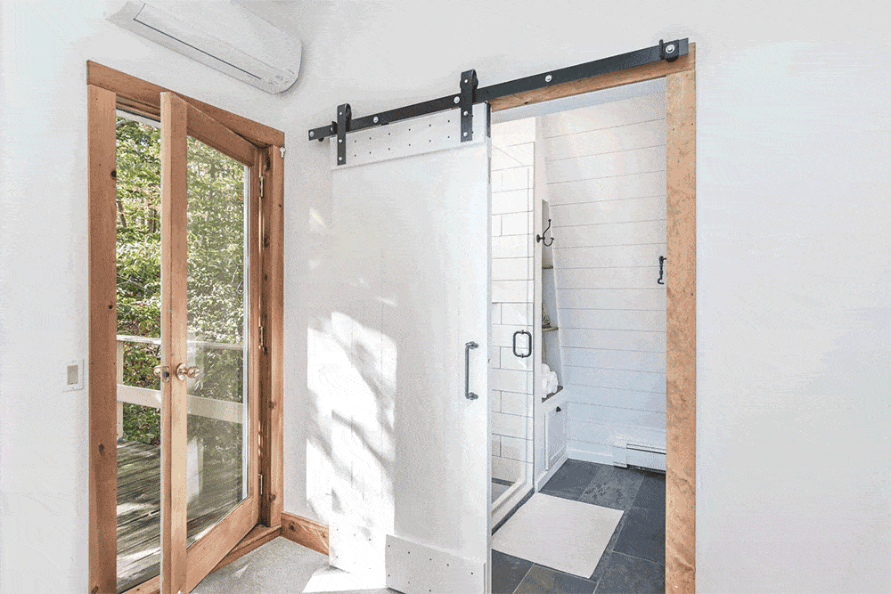 White sliding barn door in a white bedroom with brown french windows after renovation